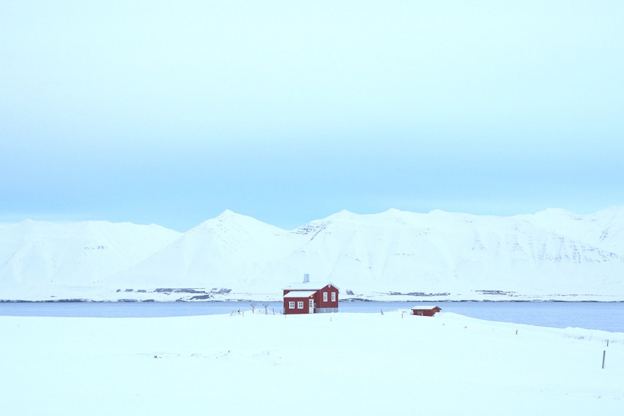 A lonely house among snowy mountains stands in Dalvik.