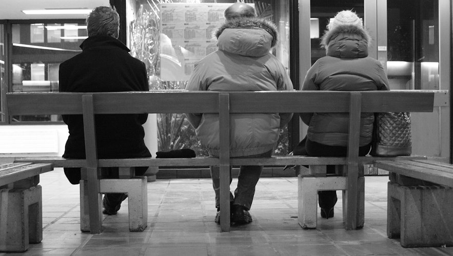 Trzy osoby czekają na autobus w Hlemmur.