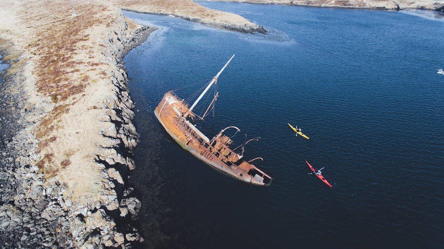 Kayakers pass a shipwreck in Iceland.
