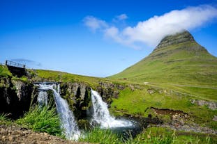 The stunning Mount Kirkjufell on a sunny day with waterfalls in the foreground.