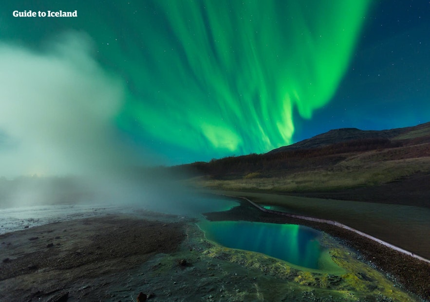แสงออโรร่าที่สดใสส่ายอยู่เหนือภูมิประเทศที่เต็มไปด้วยหิมะของประเทศไอซ์แลนด์