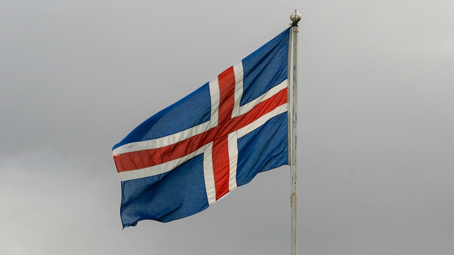 Iceland's flag flies against stormy skies.