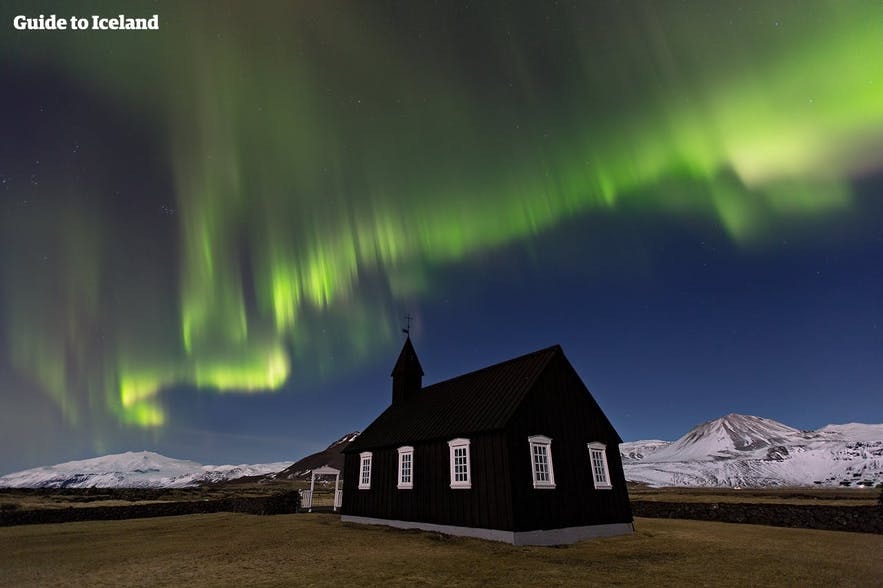 A small church sits under the aurora borealis.