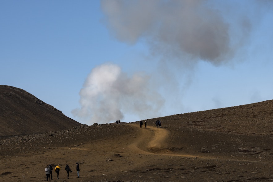 Aufsteigende Rauchwolken über dem Weg, der Besucher zum Vulkn Fagradalsfjall im Süden Islands führt.