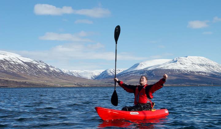 A kayaker cheers in the fjord of Eyjafjordur.