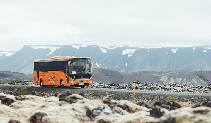 The Airport Direct transfer bus travels from Keflavik Airport to Reykjavik with snow sprinkled on the surrounding Reykjanes peninsula landscape.