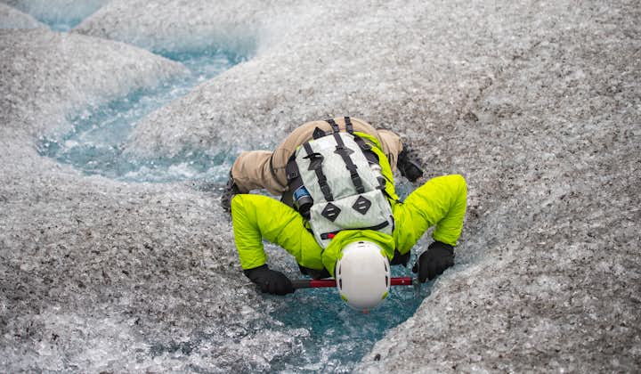 A guest on the glacier hiking tour gets up close to the glacial water.