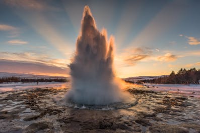 The geyser Strokkur erupts, sending a stream of water into the air.