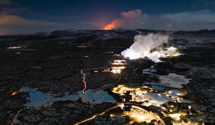 A volcano erupts behind the Blue Lagoon.