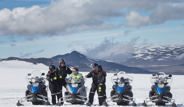 Snowmobiles in a line with happy drivers stopping for a break.