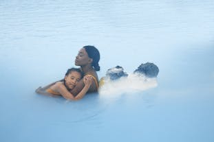 Ein Elternteil und ein Kind genießen die Wärme der Blauen Lagune.