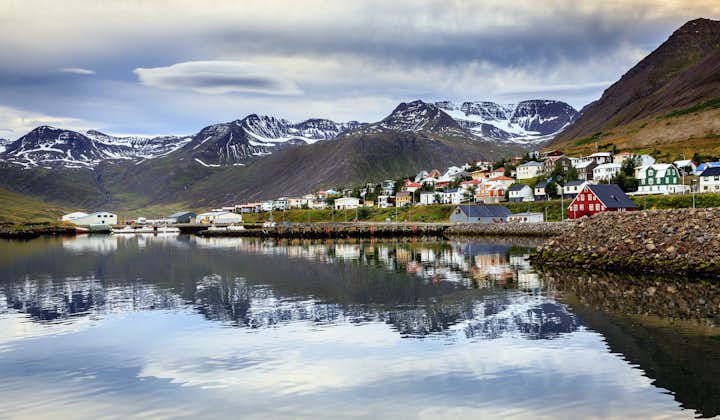 Waterfront view of Siglufjordur village with the mountains behind and the houses reflecting onto the water.