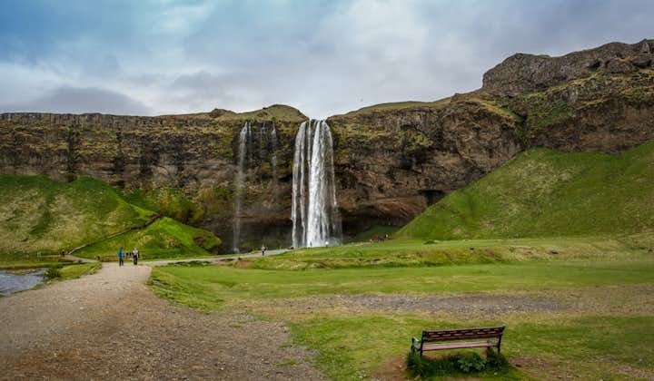 Skogafoss waterfall has a bench in the foreground.