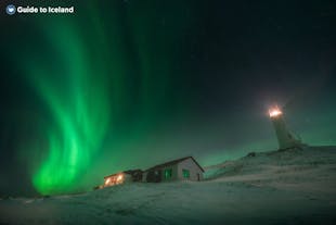 Las auroras se arremolinan sobre una casa a lo lejos en Islandia.