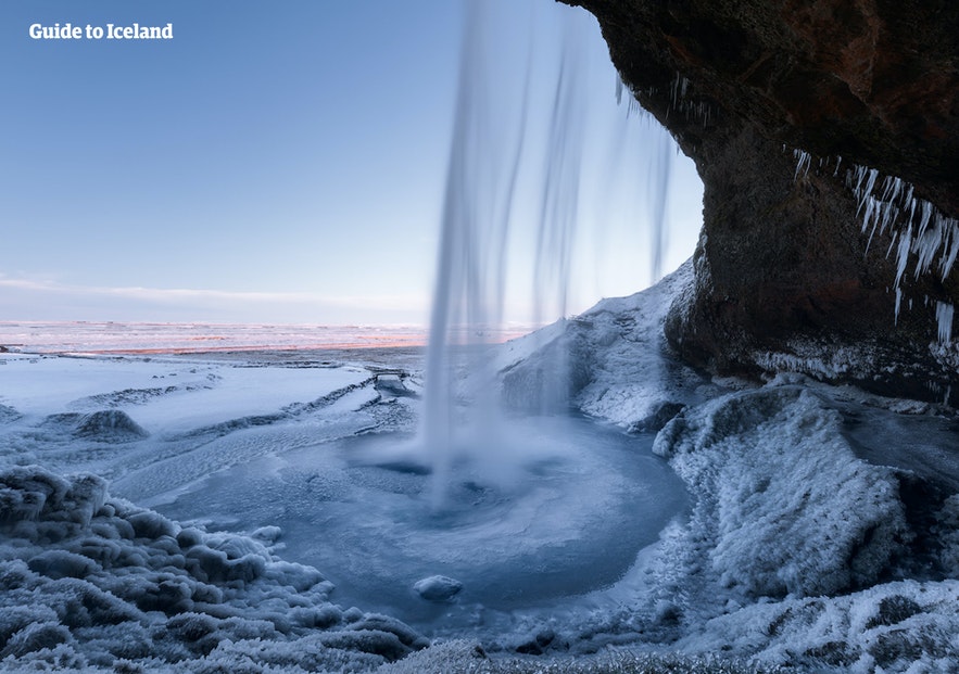 Snow settles behind the waterfall of Seljalandsfoss.