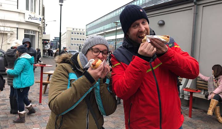 Two people eating a traditional Iceland hot dog.