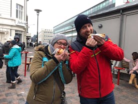 Two people eating a traditional Iceland hot dog.
