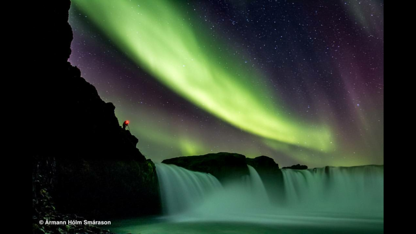 Green northern lights showing over waterfall in Iceland.
