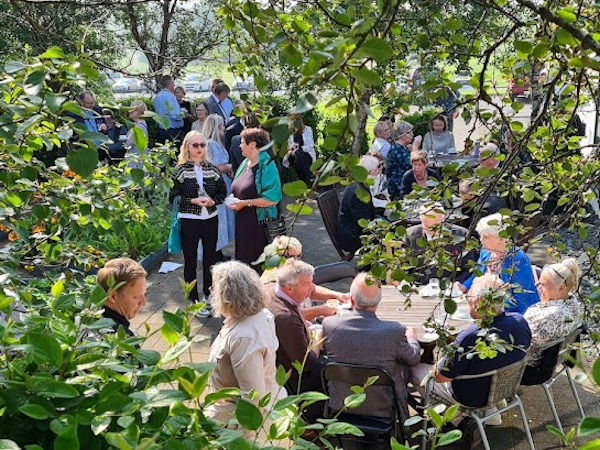 Groups of people enjoy meeting in the leafy green outdoor area at Hotel Skalholt.