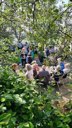 Groups of people enjoy meeting in the leafy green outdoor area at Hotel Skalholt.