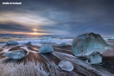 Giant icebergs stranded on Diamond beach with the sea stretched beyond.