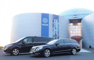 An executive Mercedes and a people carrier outside a glass building.