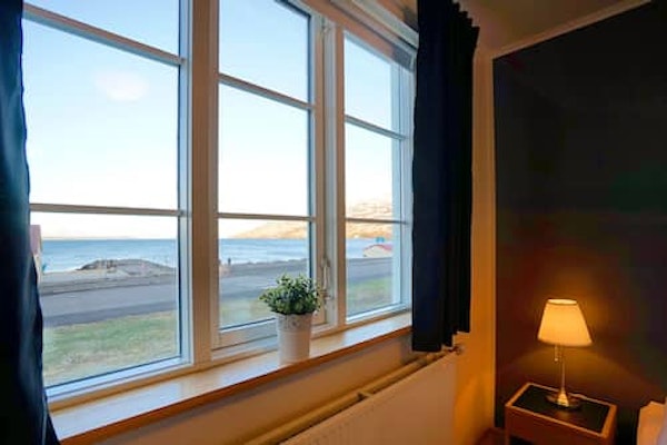 A bedroom window with mountain and fjord views at Grenivik Guesthouse.
