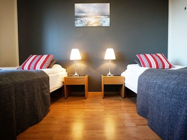 A twin room at Grenivik Guesthouse, with bedside tables and lamps, and a picture on the wall.