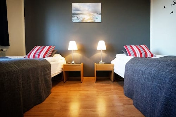 A twin room at Grenivik Guesthouse, with bedside tables and lamps, and a picture on the wall.