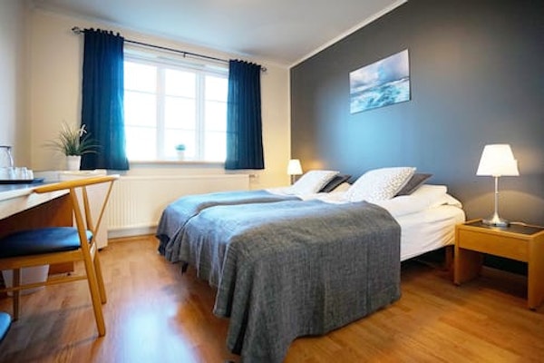 A double room at Grenivik Guesthouse, with a large window and the curtains open.