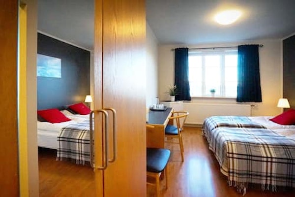 A double room with a desk and chair at Grenivik Guesthouse, showing a reflection of the bed from the wardrobe mirror.