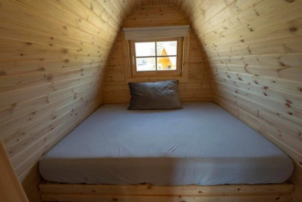 A double bed, and the wooden interior of a Fossatun camping pod.