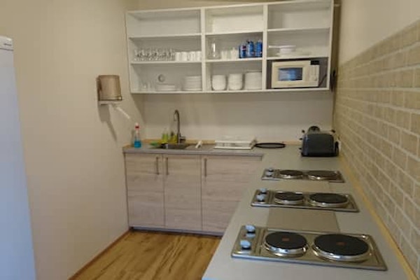 A well-equipped shared kitchen at Fossatun camping pods with stovetops, a toaster, microwave, and kitchenware.