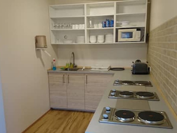 A well-equipped shared kitchen at Fossatun camping pods with stovetops, a toaster, microwave, and kitchenware.