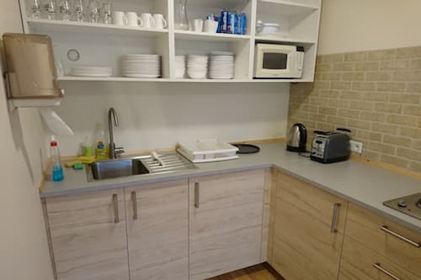 A well-equipped shared kitchen at Fossatun camping pods with a toaster, electric kettle, microwave, and kitchenware.