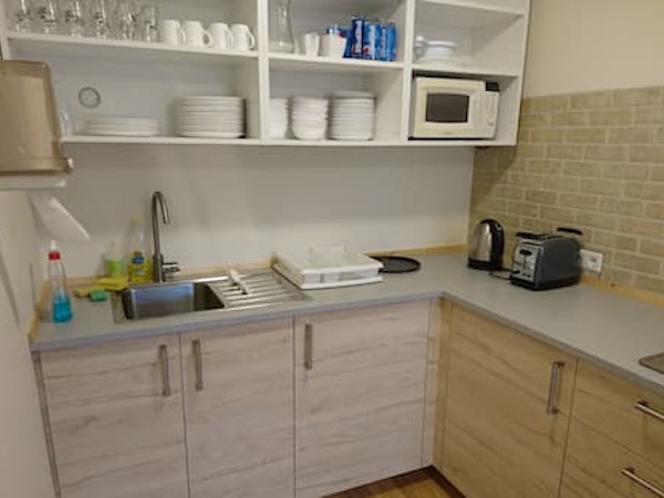 A well-equipped shared kitchen at Fossatun camping pods with a toaster, electric kettle, microwave, and kitchenware.