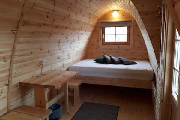 A bed and table inside a rounded-roof Fossatun camping pod.