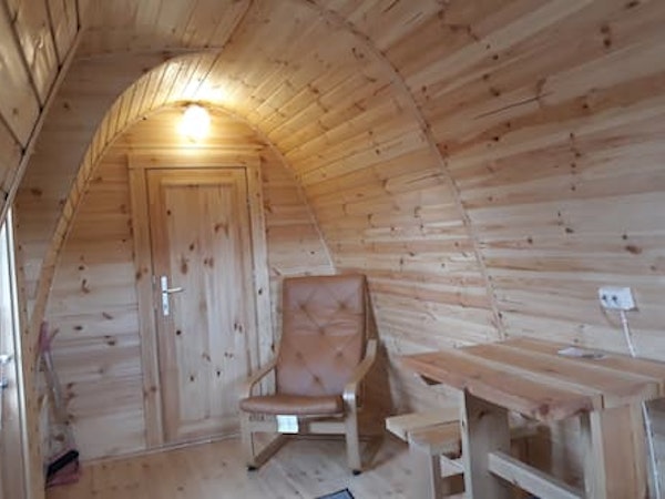 A corner chair and table inside a Fossatun camping pod.