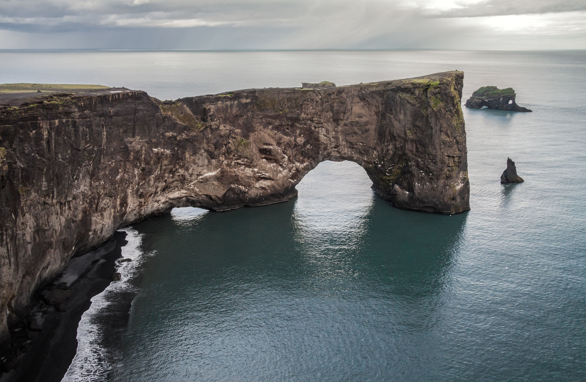 The black arch of lava in Dyrholaey stretches out to sea.
