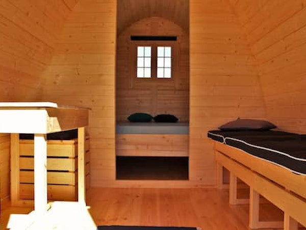 Beds and the wooden interior of a Fossatun camping pod.