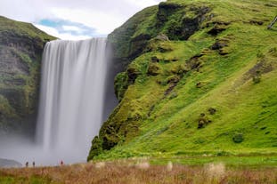 The magnificent Skogafoss waterfall creates a misty spray as it tumbles down from a moss-covered cliff.