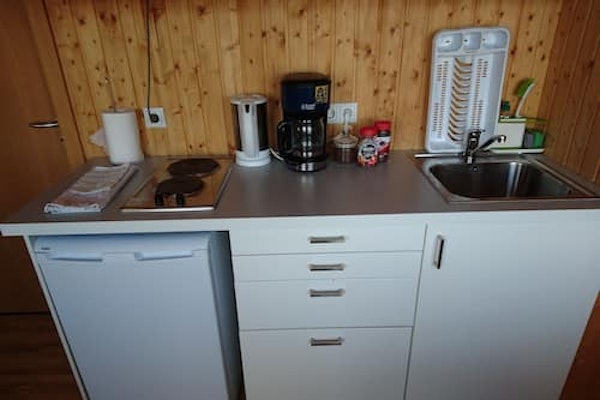 A close-up view of the bench area in the Fossatun Sunset Cottage with a fridge, coffee maker, kettle, tea, coffee, and sink.