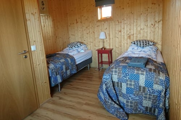 Two single beds with towels and a bedside table and lamp in a room at Fossatun Sunset Cottage.