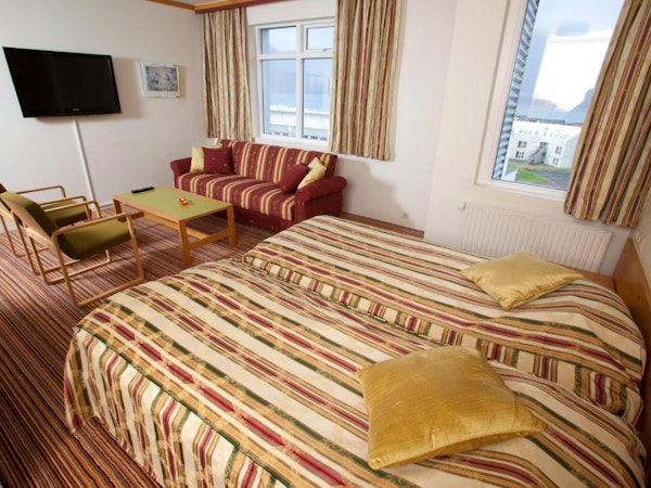Hotel Borgarnes bedroom with sofa and tv.