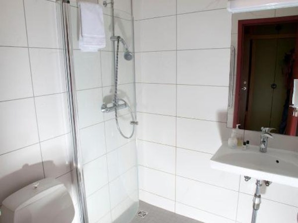Hotel Borgarnes bathroom with toilet, shower, and sink.
