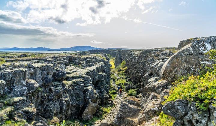 People are walking along a path amid a rocky landscape at Thingvellir National Park.