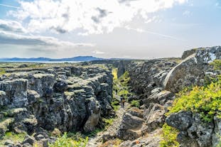People are walking along a path amid a rocky landscape at Thingvellir National Park.