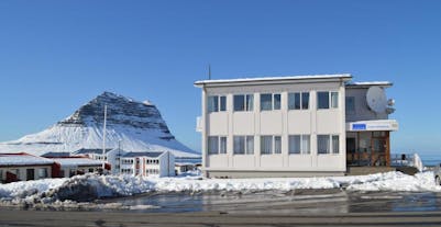 The Old Post Office Guesthouse in the snow with Kirkjufell behind it.