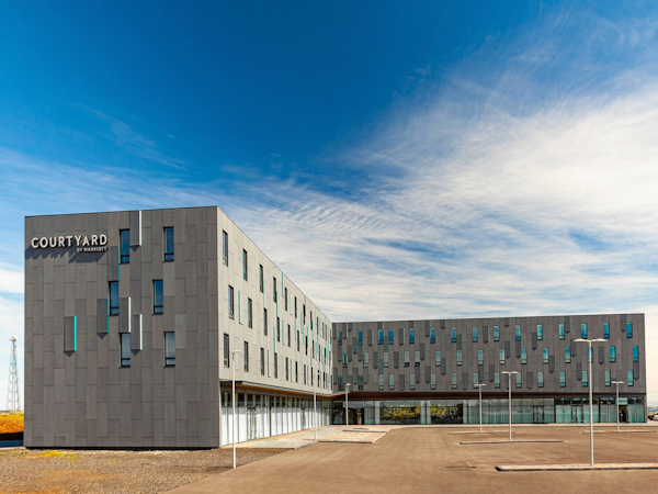 Exterior view of the Courtyard by Marriott Reykjavik Keflavik Airport on a bright and cloudy blue-sky day.