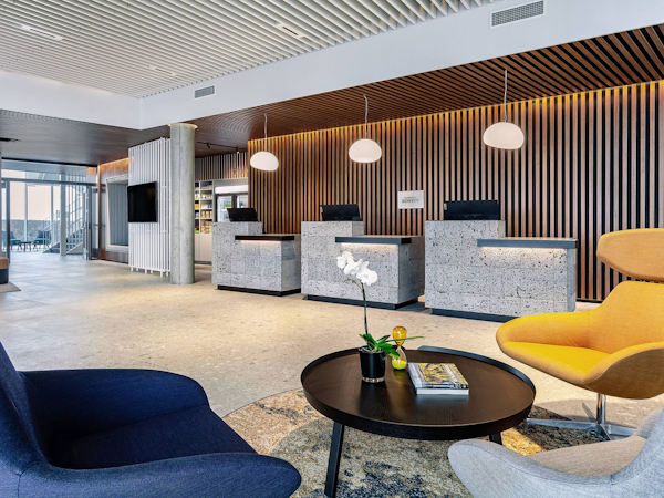 The reception area with comfortable chairs and a table at the Courtyard by Marriott Reykjavik Keflavik Airport.
